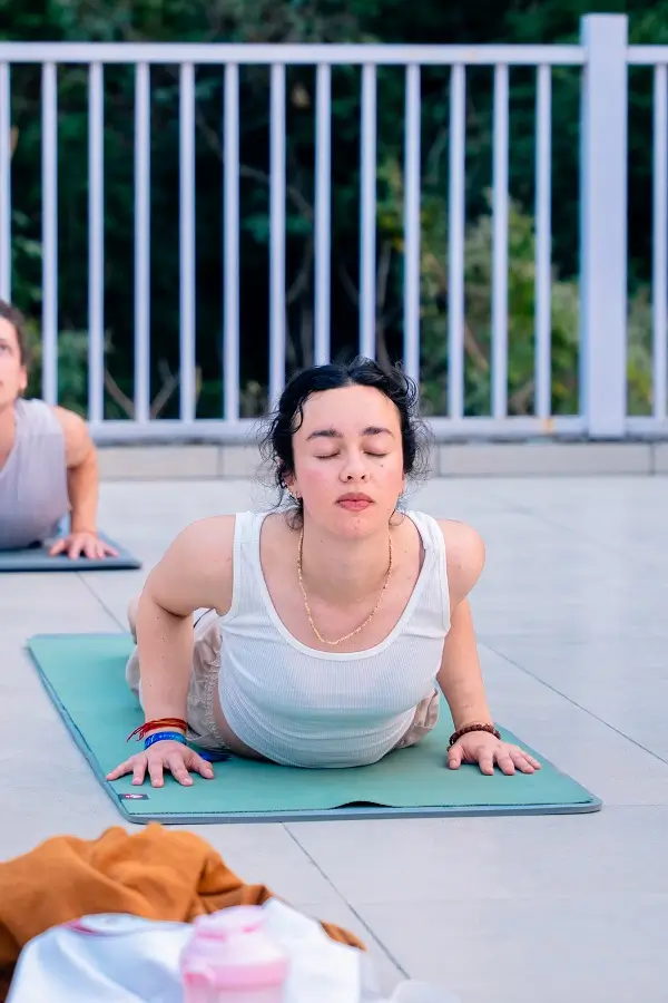 Two students holding tree pose side by side on the terrace at dawn